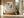 Framed beige and gray abstract artwork above a built-in bench beside tall windows.
