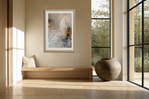 Framed beige and gray abstract artwork above a built-in bench beside tall windows.