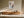 Light-framed layered abstract wall art above a long wooden sideboard in sunlight.