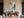 Framed textured abstract artwork above a fireplace set for dining with wine glasses.