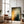 Large unframed Copper Veil canvas leaning against a wall beside a leather chair and floor lamp.