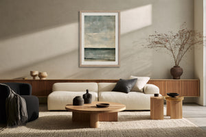 Framed blue-grey abstract artwork above a cream sofa and low wooden coffee table.