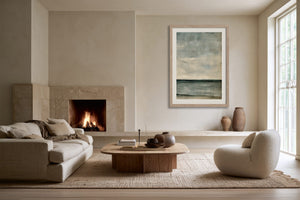 Framed blue-grey abstract artwork in a living area with fireplace, sofa, and round chair.