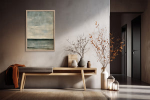 Framed blue-grey abstract artwork above a wooden console with vases and dried branches.