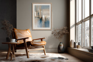 Framed blue and beige abstract artwork above a leather armchair beside a large window.