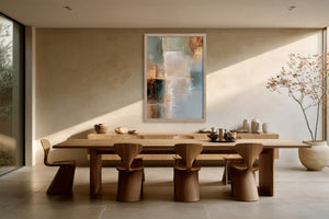 Framed abstract artwork displayed above a long wooden dining table and sculptural chairs.