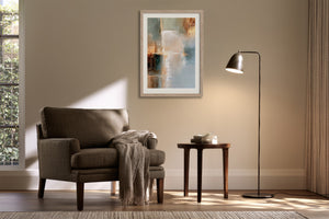 Framed abstract wall art above an upholstered armchair beside a floor lamp.
