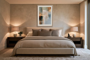 Framed Copper Shore abstract art centered above a bed between two bedside tables.