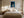 Framed blue abstract artwork with a glowing arch hangs above a bed between two windows.