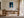 Framed blue abstract artwork with a pale arch displayed above a wooden desk.