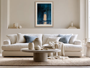 Framed blue abstract artwork with a pale arch hangs above a cream sofa.