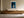 Framed blue abstract artwork with a glowing arch hangs above a long wooden sideboard.