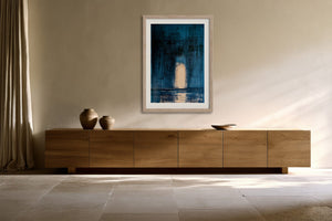 Framed blue abstract artwork with a glowing arch hangs above a long wooden sideboard.