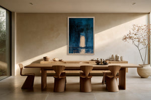 Framed blue abstract artwork with a pale arch above a long wooden dining table.