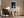 Framed blue abstract artwork with a pale arch above an armchair and side table.