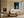 Framed blue abstract artwork with a pale arch hangs above a cream sofa near a fireplace.