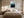Light wood-framed blue mountain artwork centered above a bed between matching bedside lamps.