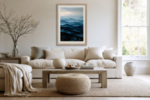 Light wood-framed mountain artwork above a white sofa and wooden coffee table.