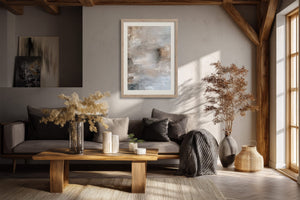 Framed pale gray and beige abstract artwork above a dark sofa in a wood-beamed living area.