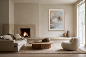 Framed pale abstract artwork displayed above a fireplace in a neutral living room.