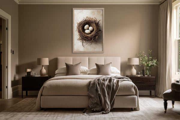 Framed bird nest artwork with three speckled eggs centered above a bed between matching bedside tables.