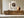 Framed bird nest artwork with three speckled eggs above a low wooden sideboard and large ceramic vase.