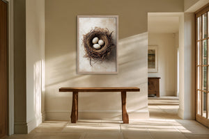 Framed bird nest artwork with three speckled eggs above a rustic wooden bench in a sunlit hallway.