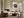 Framed bird nest artwork with three speckled eggs above a fireplace in a softly furnished living room.