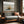 Dune grass coastal artwork in a dark wood frame above a gray sofa by a window.