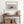 Dune grass artwork in a pale wood frame above a rustic console with woven baskets.