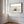 Close view of dune grass artwork in a warm wood frame on a sunlit white paneled wall.