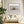 Dune grass artwork in a pale wood frame above a cream sofa with white cushions and curtains.