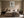 Framed windmill wall art centered above a beige bed between two dark nightstands.