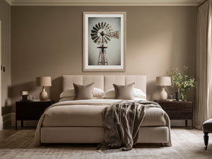 Framed windmill wall art centered above a beige bed between two dark nightstands.