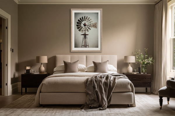 Framed windmill wall art centered above a beige bed between two dark nightstands.