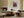 Light wood-framed red-leaved tree artwork above a low sofa beside a lit fireplace.