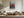 Light wood-framed red-leaved tree artwork above a sectional sofa and wooden coffee table.