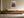 Light wood-framed red-leaved tree artwork above a long wooden sideboard with ceramic vessels.