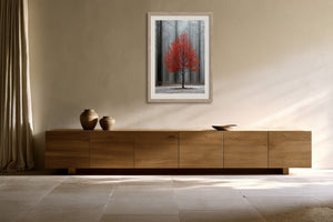 Light wood-framed red-leaved tree artwork above a long wooden sideboard with ceramic vessels.