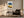 Light wood-framed coastal watercolour above a dark armchair, side table, and black floor lamp.