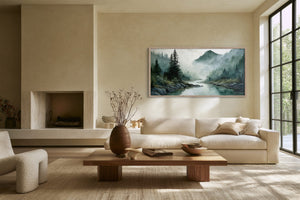 Framed misty mountain river watercolor above a cream sofa and low wood coffee table.