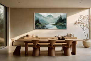 Framed mountain river watercolor above a long wooden dining table and sculptural chairs.