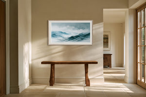 Framed watercolor mountain artwork above a rustic wooden bench in a sunlit hallway.