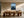 Light wood-framed rowboat artwork displayed above a long wooden dining table and sculptural chairs.