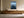 Light wood-framed rowboat artwork above a long wooden sideboard with ceramic vessels.