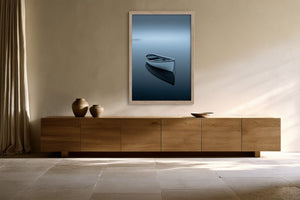 Light wood-framed rowboat artwork above a long wooden sideboard with ceramic vessels.