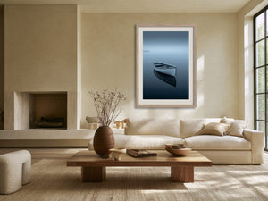 Light wood-framed rowboat artwork above a cream sofa and low wooden coffee table.