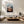 Light wood-framed mountain valley artwork above a low white sofa and wood coffee table.