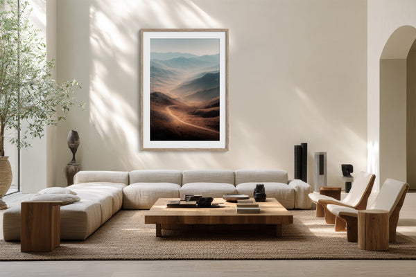 Light wood-framed mountain valley artwork above a low white sofa and wood coffee table.