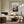 Light wood-framed mountain valley artwork above a fireplace and cream seating near grid windows.